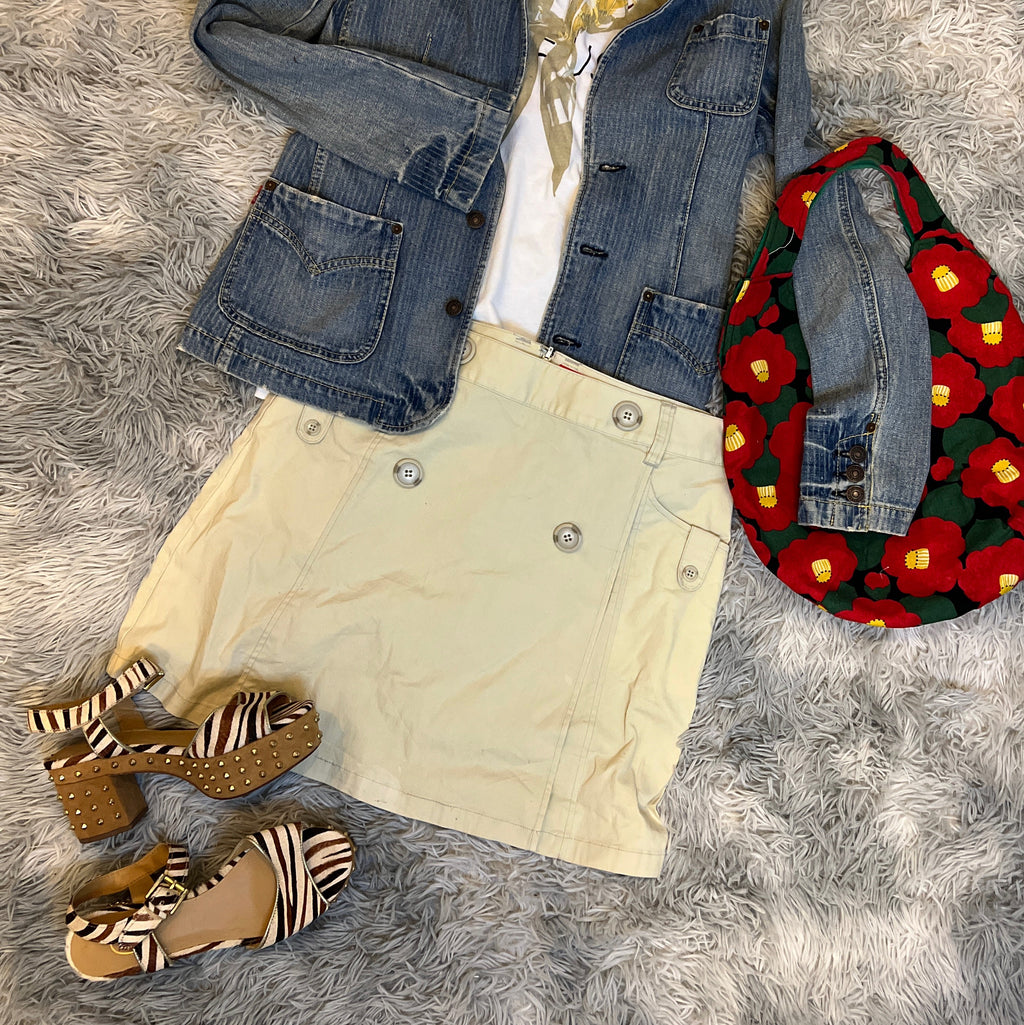 Clothing items including a jacket, jeans, shoes, and a hat on a gray textured surface.