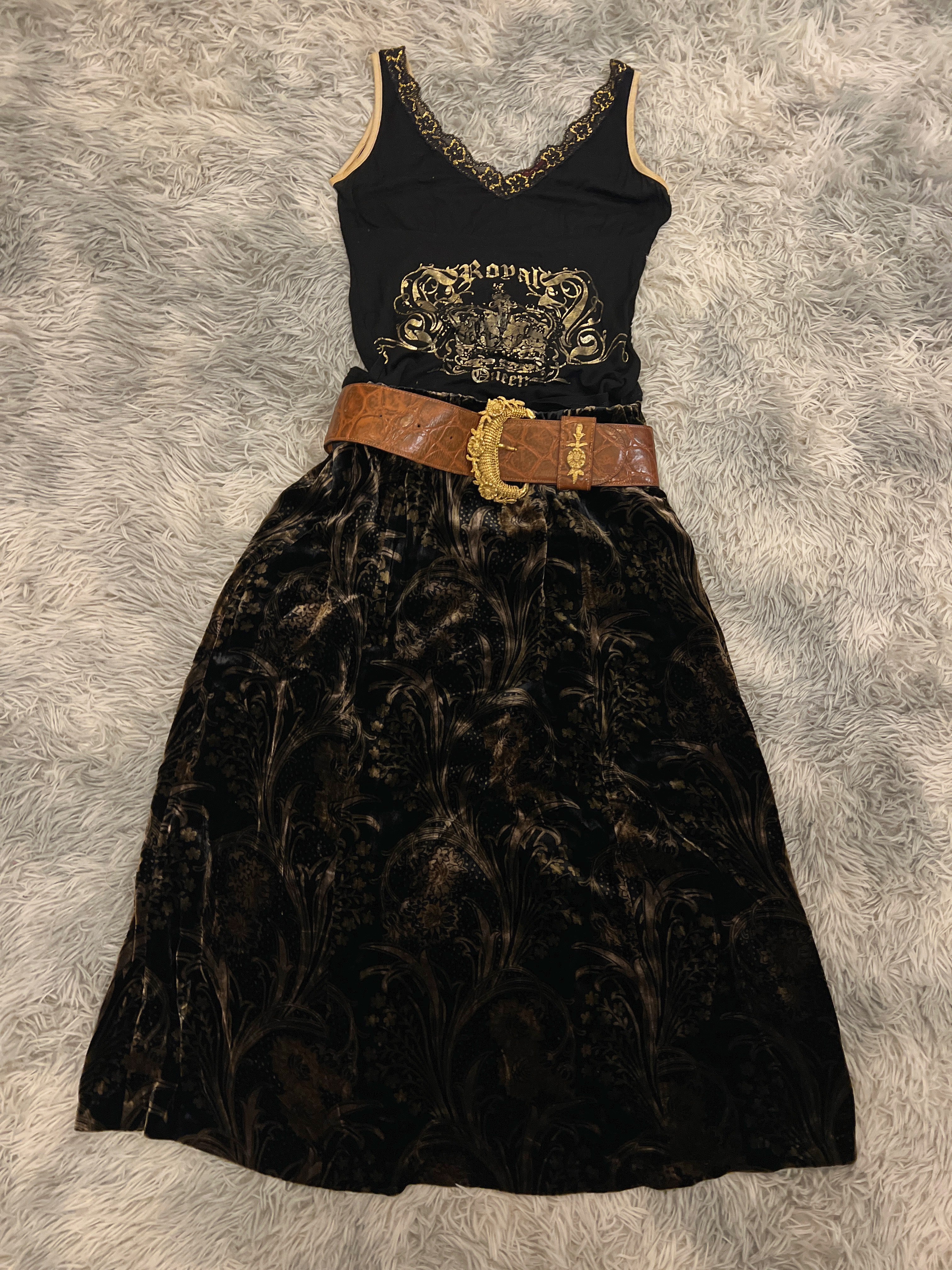 Black sliveless t-shirt with velvet skirt gold embroidery and a brown belt on a textured gray background