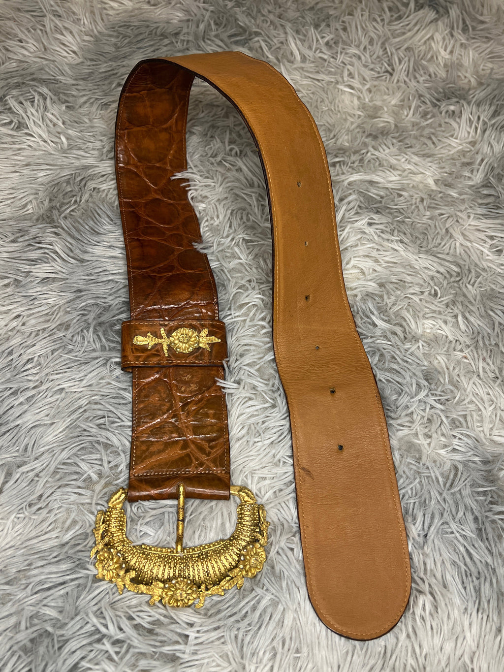 Brown leather belt with gold buckle on a gray textured background